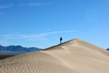 Fototapeta na wymiar Lone hiker explores the desert sand dunes