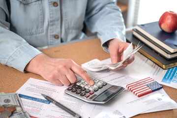 Individual income tax return. Woman work with financial papers at home count on calculator before...