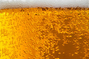 Light beer with foam in a glass. Bubbles close up.