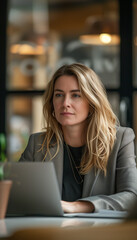 a partner, woman, mid 30s, at a management consulting firm sitting in a meeting in front of her laptop at the office