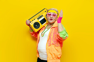 funny crazy granny in hipster clothes listening to music on tape recorder and singing on yellow...