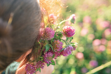Womans face and red clover flowers in the rays of the sun in a clover field. Useful herbs and...