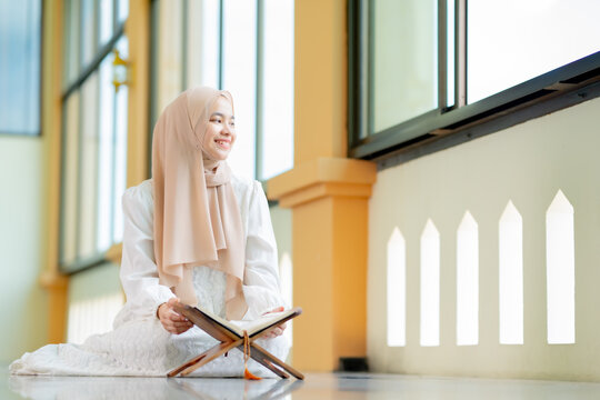 Ramadan, quran, The image of an Asian Muslim woman in the Islamic religion in hijab in cream color. reading the Quran and having a happy Staying in a beautiful mosque, Arabic word Holy Al Quran.