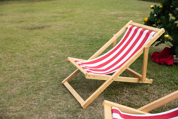 red and white striped deckchairs on green grass on backyard.