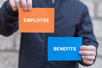 Man holding multi-colored paper cards sees text: EMPLOYEE BENEFITS. Concept of employee benefits. Containing social security, pay raise, health and life insurance, paid vacation, bonus and more.