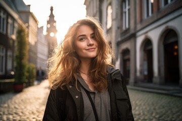 Fototapeta premium Fashion-forward woman in a charcoal vest strolling down a cobblestone street in a historic town
