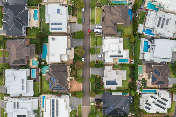 Aerial top down view of suburban street lined with modern prestige homes with pools and rooftop solar, Sydney, Australia