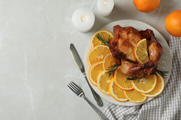 Baked chicken served with orange slices on light marble table, flat lay