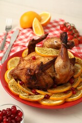 Baked chicken with orange slices on white wooden table, closeup