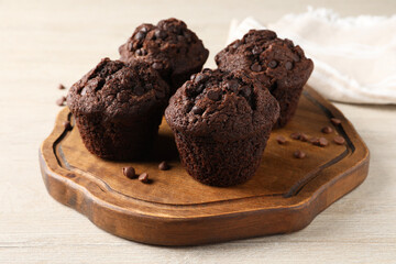 Delicious chocolate muffins on white wooden table