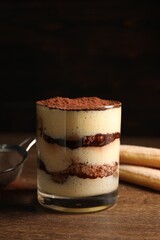 Delicious tiramisu in glass on wooden table