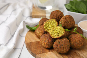 Delicious falafel balls, herbs and sauce on table