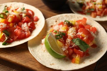 Delicious tacos with vegetables, lime and ketchup on wooden table, closeup