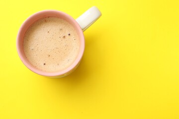 Aromatic coffee in cup on yellow background, top view. Space for text