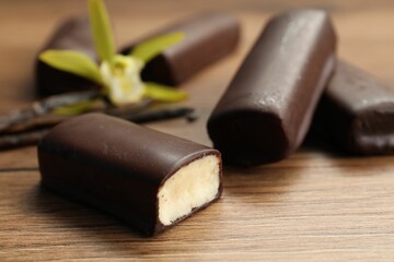 Glazed vanilla curd cheese bars on wooden table, closeup