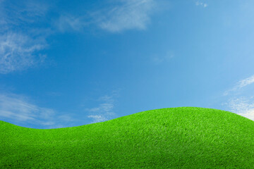 Lush green grass under blue sky with clouds