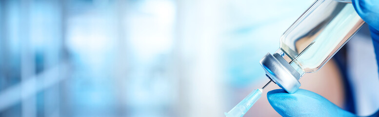 Doctor filling syringe with medication from glass vial on blurred background, closeup. Banner design