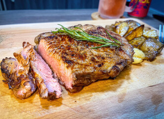 Grilled beef steak with rosemary and potatoes on a wooden board