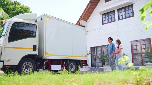 Asian young couple look at truck car while moving to new house together. 
