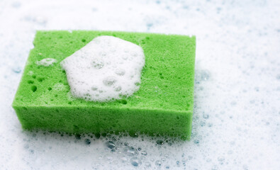 Cleaning sponge in foam of dishwashing liquid. Washing dishes concept