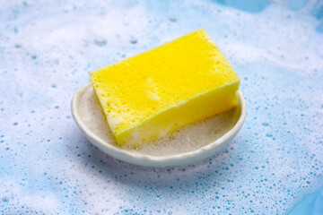 Bowl with cleaning sponge in foam of dishwashing liquid. Washing dishes concept