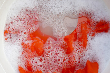 Women's dress soaked in water dissolved detergent with white foam bubble. Laundry concept