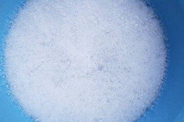 Water dissolved detergent with white foam bubble in blue basin