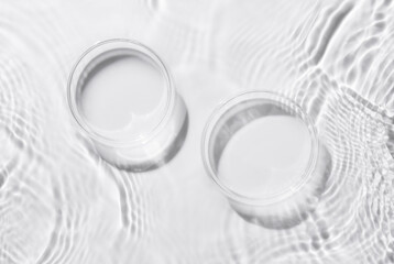 Two Petri dishes on a rippled white background. Abstract nature background of product presentation....