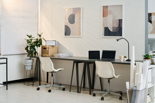 No people shot of modern office interior with minimalistic furniture and abstract paintings on walls