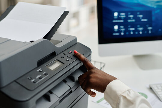 Medium closeup of hand of unrecognizable African American female manager pushing button on printer