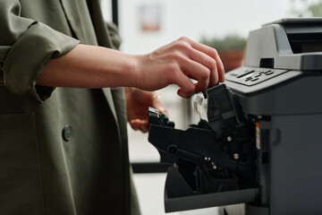Closeup of hands of unrecognizable female office worker refilling ink in printer cartridge