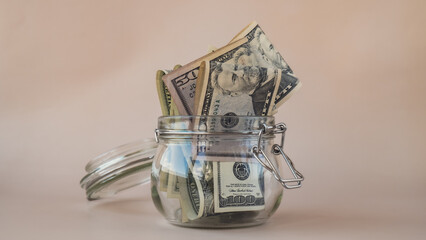 Dollar banknote saving money in glass jar on beige background. Consumption and economy Collecting money. Tips. Extra money, passive