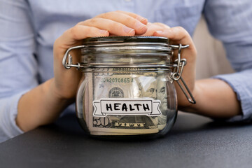 Unrecognizable woman holding Glass jar full of American currency dollars cash banknote with text...