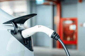 EV electric car recharge at shopping center parking lot charging in downtown city showing urban...