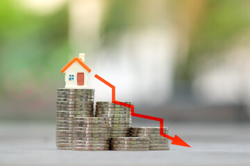 Housing finance and mortgage rates. House model on stack of coins and red arrow down, Refinance,...