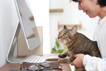 パソコンの前に座る女性と猫