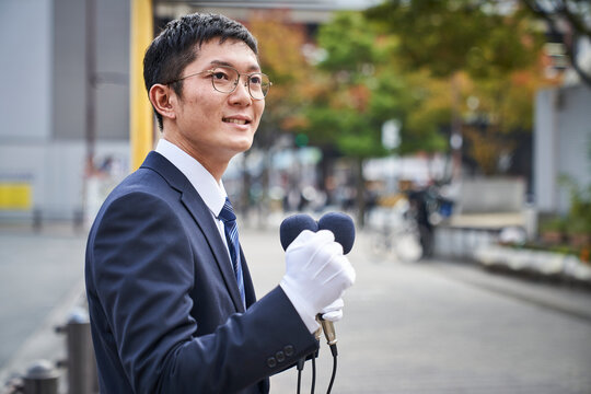 街中で演説をするスーツを着た男性