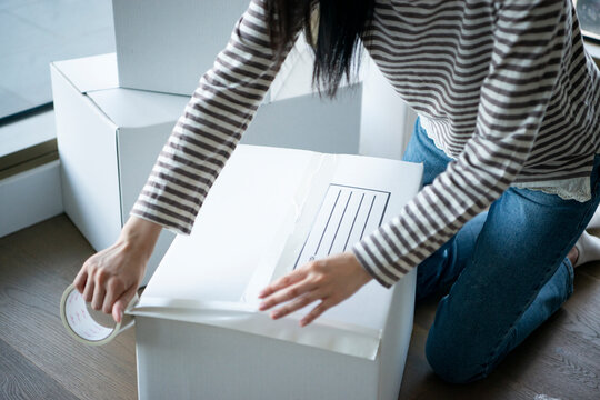 段ボールにガムテープを貼っている女性