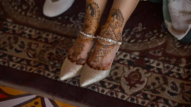 Close up of bride in wedding shoes, henna drying on Indian bride. HD footage.
