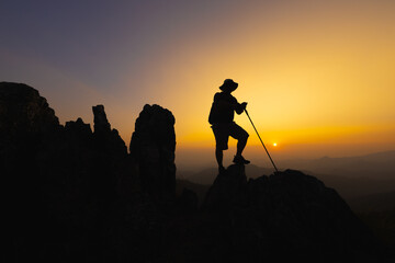 Silhouette of a Climber at the top of the rocky mountain at sunset, Man on top of mountain....