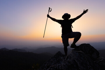 Silhouette of a Climber at the top of the rocky mountain at sunset, Man on top of mountain....