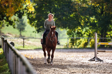 Horse woman rider riding in the sunshine at the riding arena.