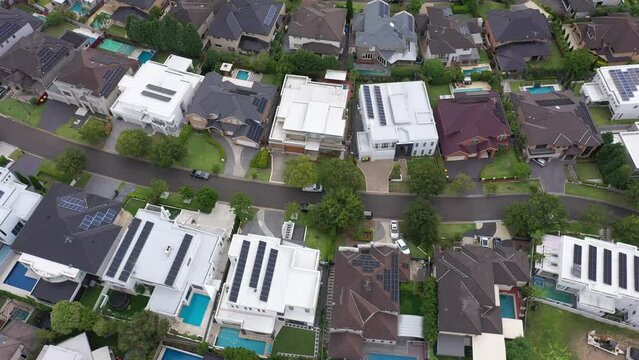 Slow circular aerial flyover of architecturally-designed modern prestige homes with rooftop solar and pools in outer suburban Sydney, Australia.