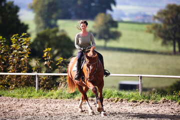 Horse woman rider riding in the sunshine at the riding arena.