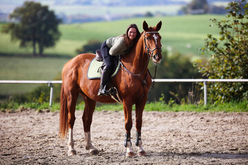 Horse woman rider riding in the sunshine at the riding arena.