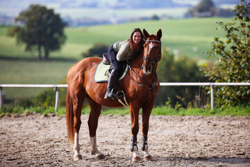 Horse woman rider riding in the sunshine at the riding arena.