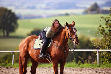 Horse woman rider riding in the sunshine at the riding arena.