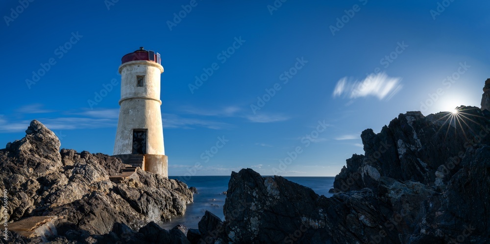 Wall mural panorama landscape view of the old capo ferro lighthouse in sardinia with a sunburst