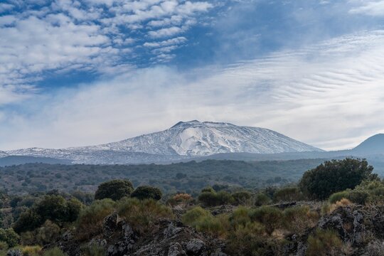 view of a snow-covered Mount Etna and the wild hills of the Sicilian backcountry