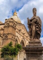 vertical view of a bishop statue and the Palermo Cathedral